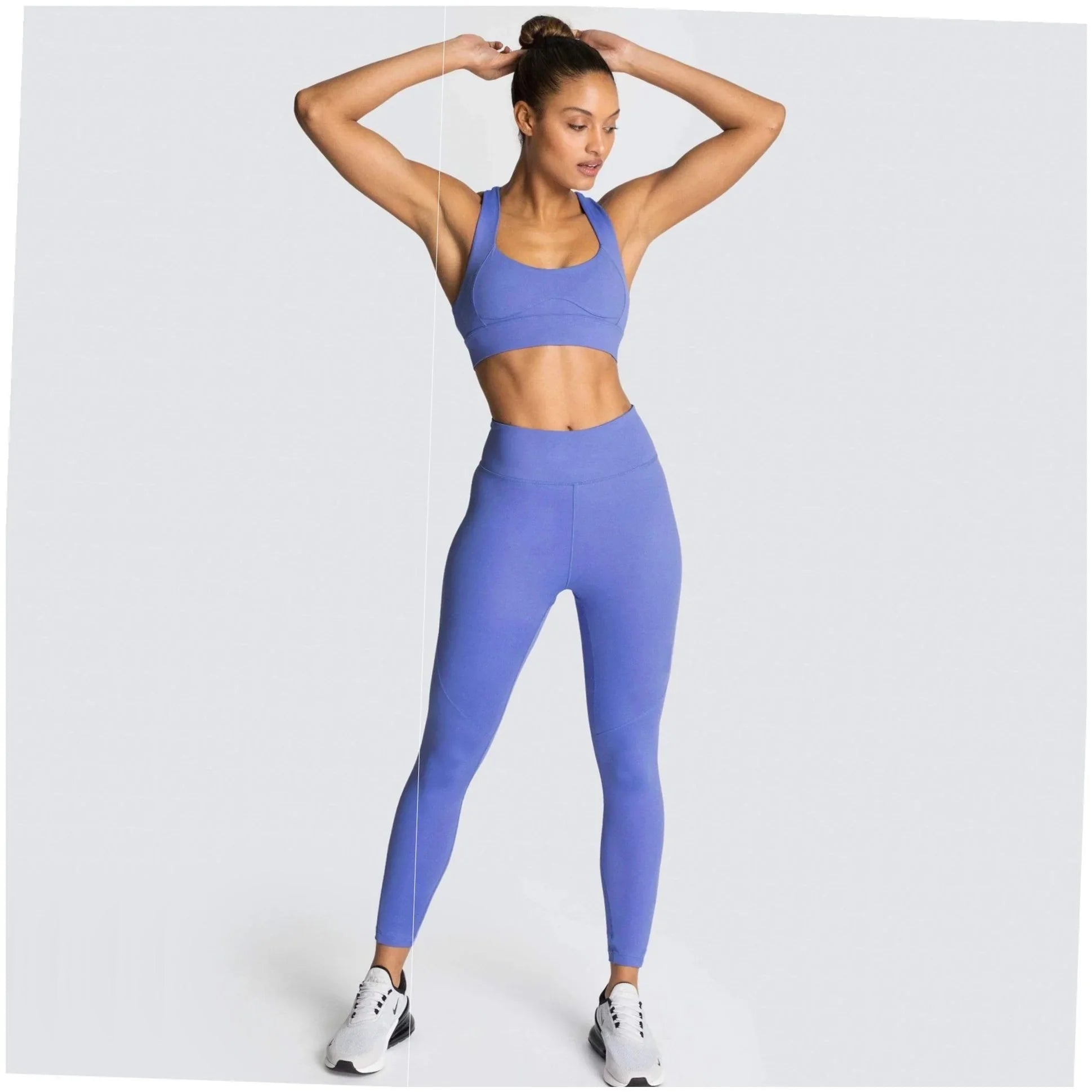 Woman in elegant periwinkle activewear set, high-waisted leggings and sports bra, poised for wellness