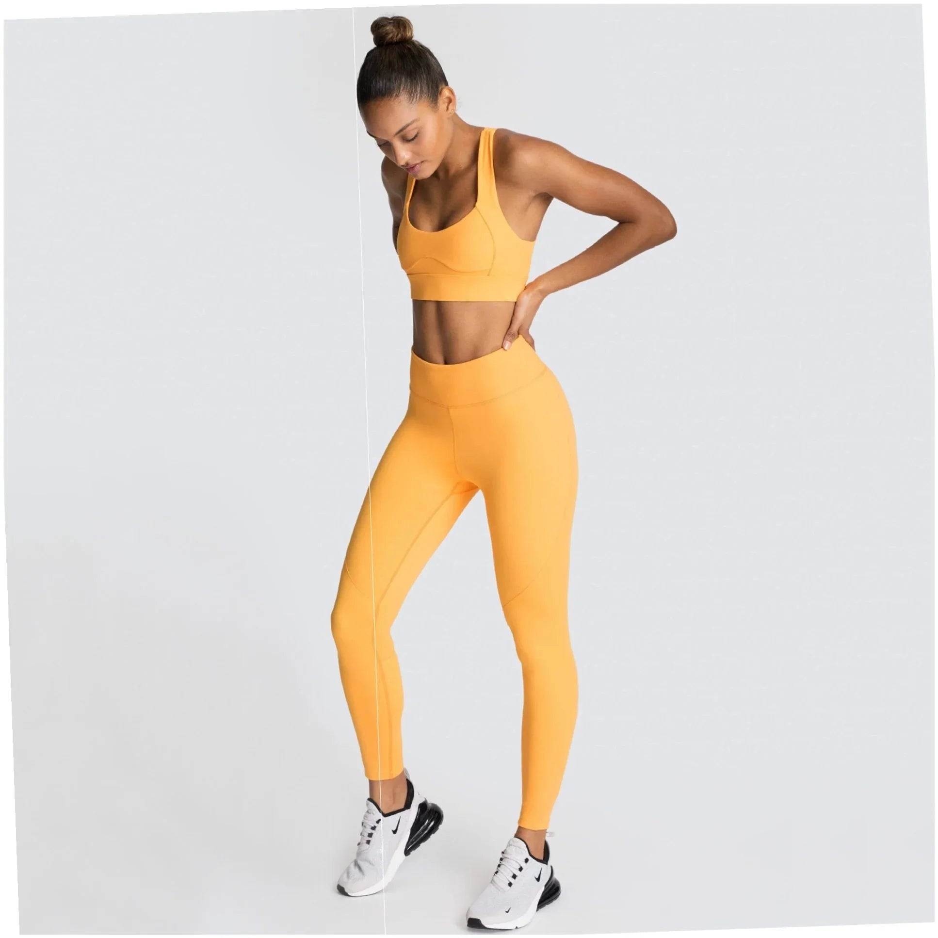 Woman in vibrant yellow activewear set, high-waisted leggings and sports bra, styled with white sneakers